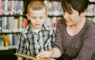A teacher reading a book to a small boy