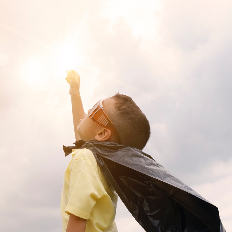 Boy wearing a cape and punching the air - showing that a dyslexia diagnosis can be empowering