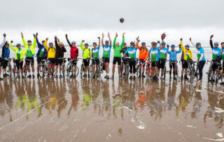 A large group of cyclists on the beach.