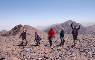 Five trekkers celebrate getting to the top of Mount Toubkal with a dance