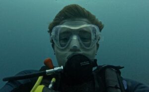 James, our young ambassador in a close-up under water picture. James is scuba diving. The image is of his eyes within this scuba mask, with air bubbles rising to the surface. 